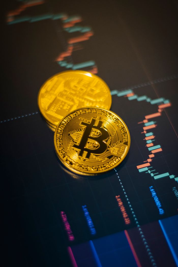 Golden Bitcoin coins on a fluctuating stock market chart background.