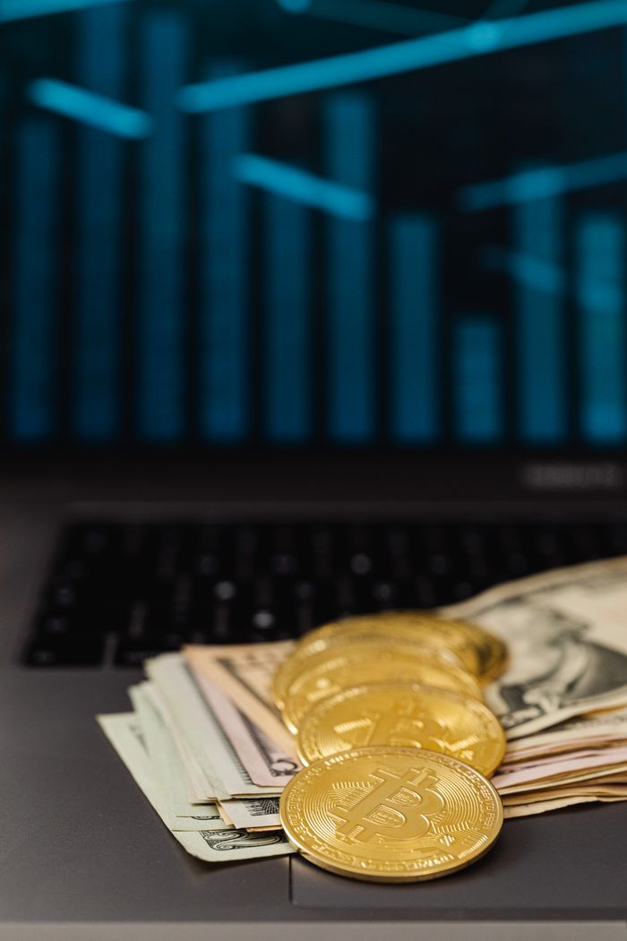 Bitcoin coins and US dollar bills on a laptop keyboard with digital data background